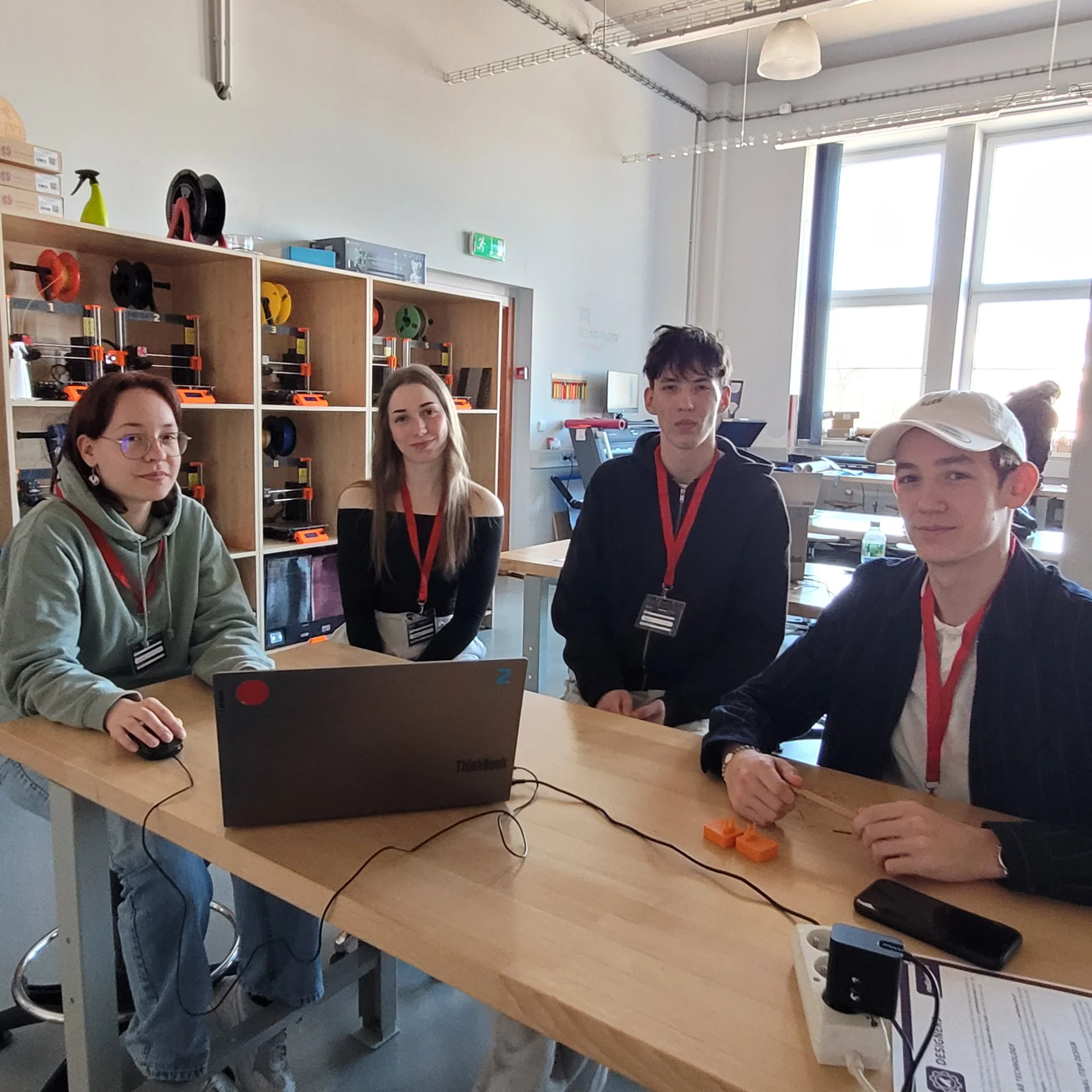 Bild: Schülergruppe am Computer zur Vorbereitung eines 3D-Druckes mit 3D Drucker im Hintergrund