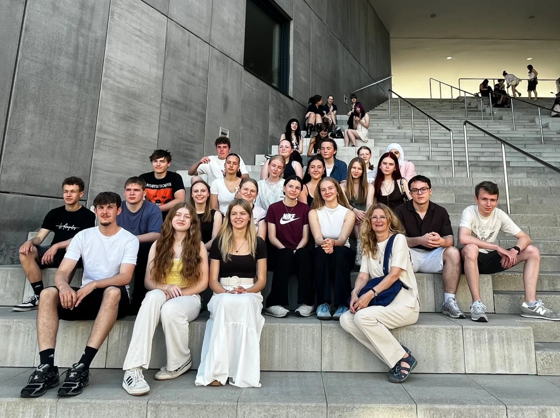 Bild: Schülerinnen, Schüler und Lehrkraft sitzen auf Treppen für Gruppenfoto.