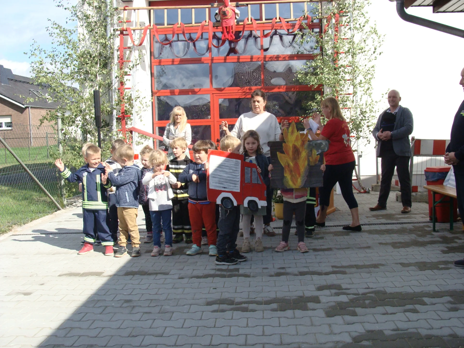 Bild: Die Kita-Kinder gestalten vor dem neuen Gerätehaus ein kleines Programm.