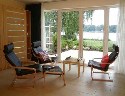 Vorschaubild: Der Wohnbereich mit lederbezogener Sitzgruppe mit Couchtisch gewährt Aussicht auf den See und einen direkten Übergang auf die Terrasse und in den Außenbereich.