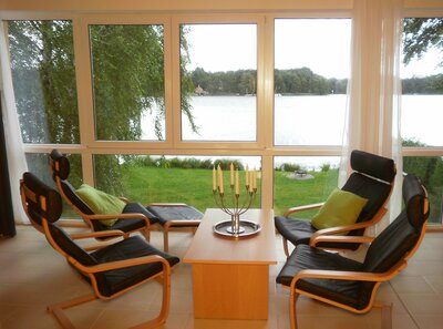 Vorschaubild: In dieser Wohnung gibt es im Wohnbereich eine lederbezogene Sitzgruppe mit Couchtisch und Panorama-Ausblick auf den Zemminsee.