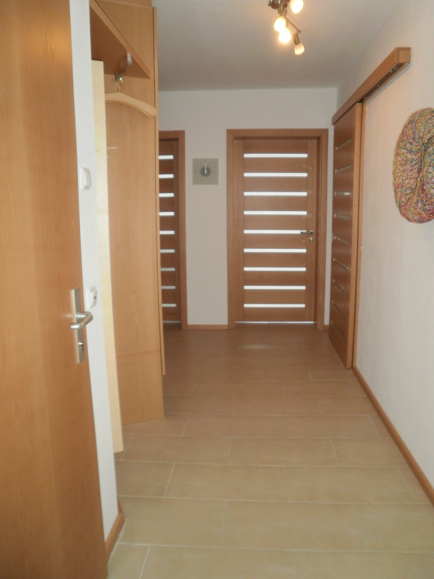 Der ger&auml;umige Flur mit Garderobe bietet zentralen Zugang zu allen Zimmern der Wohnung und zum zentralen Treppenhaus.  (Bild vergr&ouml;&szlig;ern)