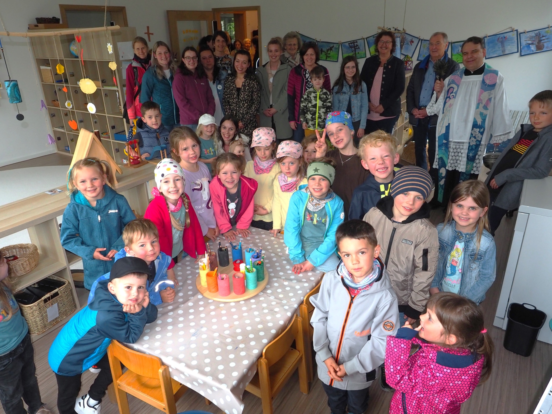 Den neu gestalteten Raum der Gruppe &bdquo;Sonnenblume&ldquo; segnete Pfarrer Josef Gallmeier (rechts, neben stv. Landrat Hermann Brandl), nachdem B&uuml;rgermeisterin Angelika Leitermann (3. v. r.) und Kindergartenleiterin Regina Brandl (an der T&uuml;re) allen gedankt hatten, die das gemeinsam geschafft hatten. 