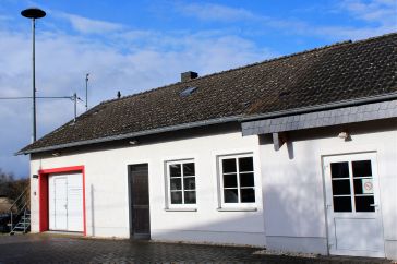Feuerwehrgerätehaus mit Sirenenmast neben Bürgerhaus
