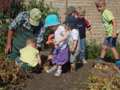 7 Kinder helfen einem Erwachsenem bei der Gartenarbeit