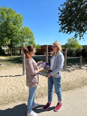 Mitarbeiterin übergibt Geschenk an Kitaleitung