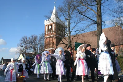 Ein Fastnachtsumzug zieht an der Werbener Kirche vorbei. Dieser ist der Mittelpunkt des Dorfes und von weitem sichtbar. Nun muss das Dach saniert werden, weshalb die Kirchengemeinde um Spenden bittet. (Bild vergr&ouml;&szlig;ern)