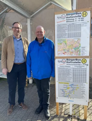 Das Haltestellenschild Nr. 1 „Barmer, Kirchenstr. 5“ im Kernort.  Die neue Linie siehe unten.  Von Links: Oberbürgermeister Sebastian Frei und Axel Jänichen vom Vereinsvorstand