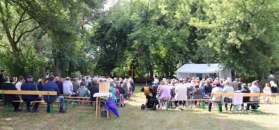 Auf einer großen Wiese an der Malxe sitzen die Menschen auf Bänken und feiern einen Taufgottesdienst. (Foto. privat) (Bild vergr&ouml;&szlig;ern)