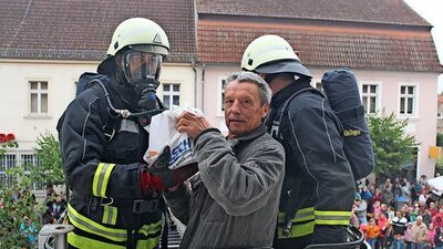 Ziesars Bürgermeister Dieter Sehm probt eine Übung mit der Feuerwehr und lässt sich im Rettungskorb der Drehleiter vor den Flammen im Rathaus in Sicherheit bringen.  © Quelle: Silvia Zimmermann