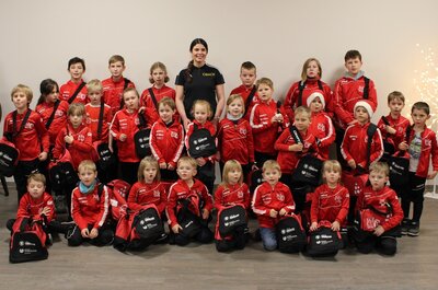 Stolz präsentieren die Mädchen und Jungen ihre neuen rot-schwarzen Trainingsanzüge und Sporttaschen. (Foto. privat)