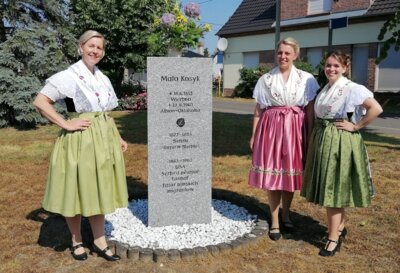 Frauen des Traditionsvereins in wendischen Trachten haben den Gedenkstein zu Ehren Mato Kosyks mit Blumen geschmückt.