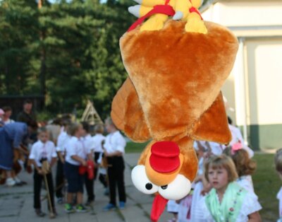 Der Plüschhahn hängt bereit, während sich im Hintergrund die Jungen mit ihren Steckenpferden bereit machen und die Mädchen anfeuern. (Bild vergr&ouml;&szlig;ern)