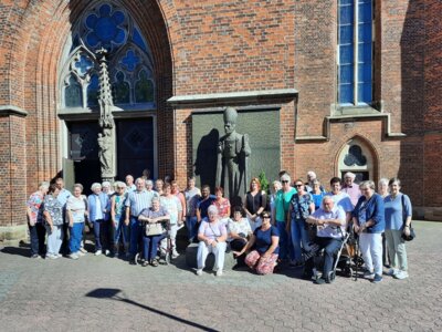 Die Besuchergruppe vor der Pfarrkirche St. Catharina und der Statue von Kardinal von Galen.