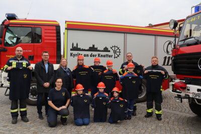 Die Mädchen und Jungen der Kyritzer Jugendfeuerwehren freuen sich gemeinsamen mit ihren Jugendwarten sowie Lars Kremmer von der e.dis (zweiter von links) sowie Bürgermeisterin Nora Görke (dritte von links) über ihre neuen T-Shirts. (c) Stadt Kyritz