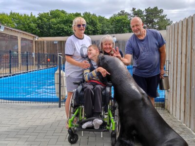 Michel Sprenger zusammen mit Seelöwe Lou dem Therapieteam Isa Burke, Physiotherapeutin Inken Planthaber und John Burke.