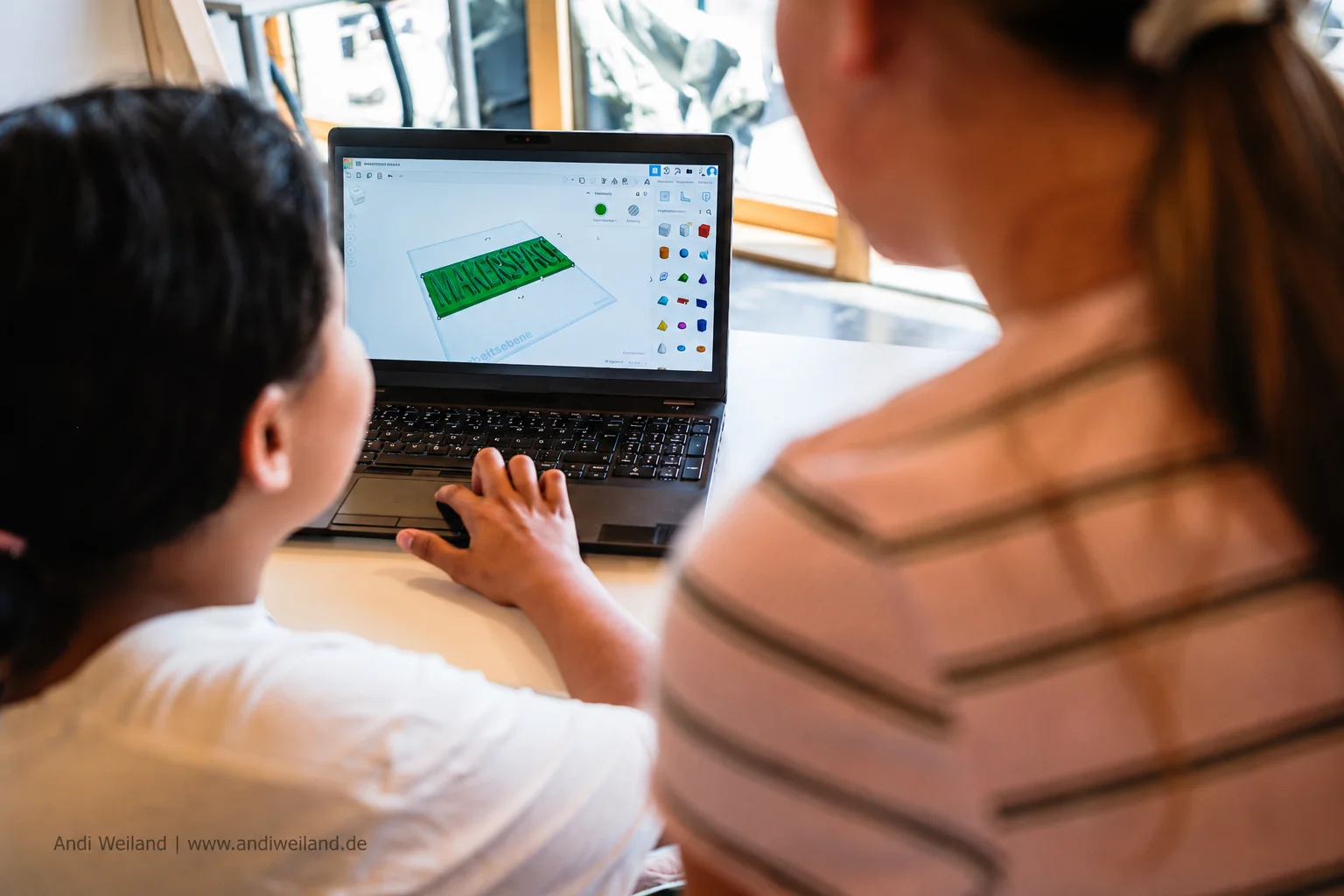 Zwei Kinder gestalten gemeinsam an einem Laptop ein 3D-Modell und sammeln praktische Erfahrungen mit digitaler Technik.