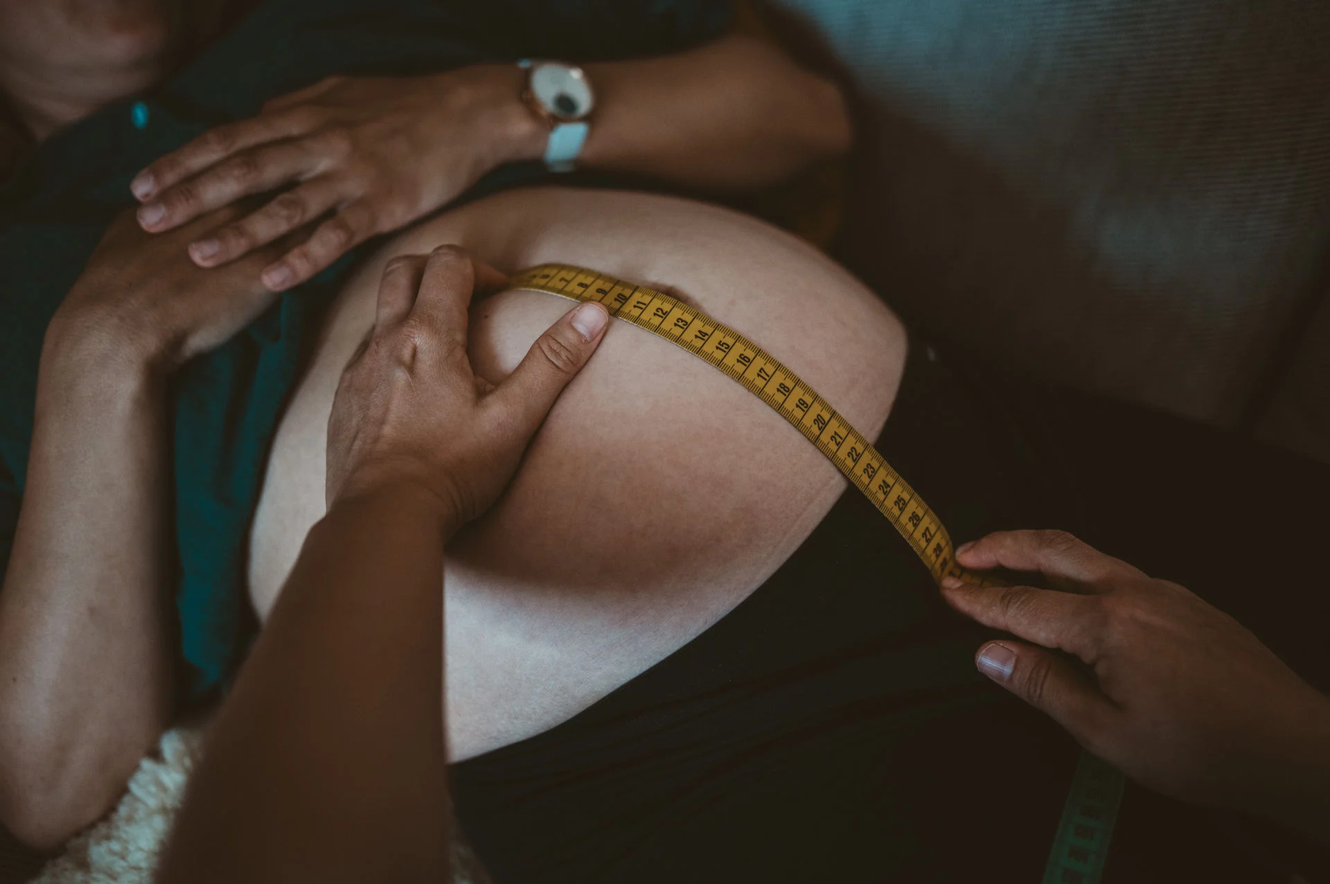 Hebamme misst den Bauch der Schwangeren
