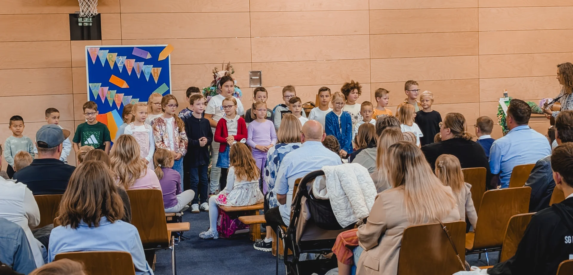 Singende Zweitklasskinder begrüßen die neuen Erstklasskinder