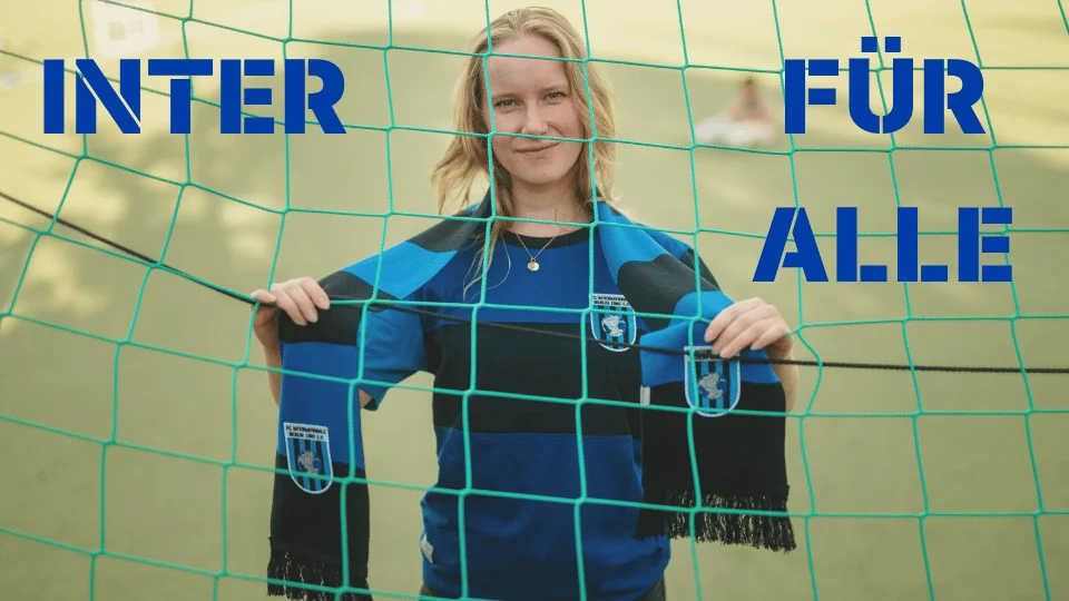 Eine Frau mit Inter Schal schaut durch das Tornetz in die Kamera