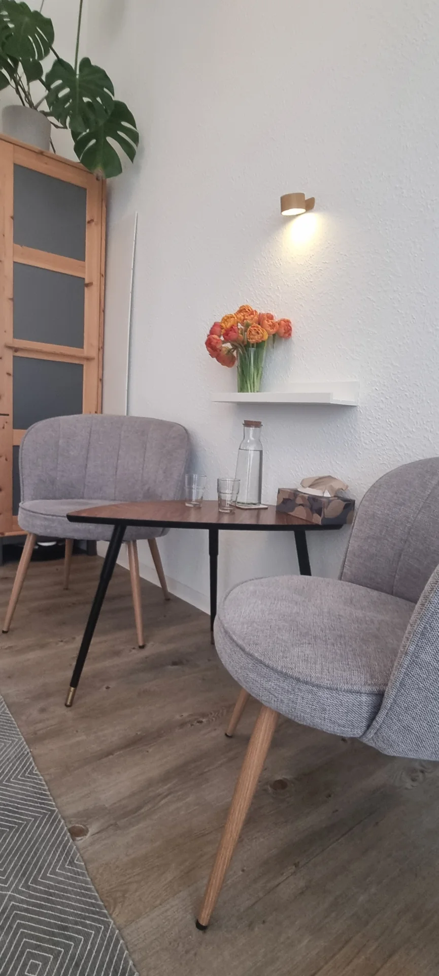 Therapieraum mit zwei grauen Sesseln und einem Tisch mit Wassergläsern