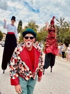 Clown und zwei Stelzengeherinnen nehmen am Festzug teil