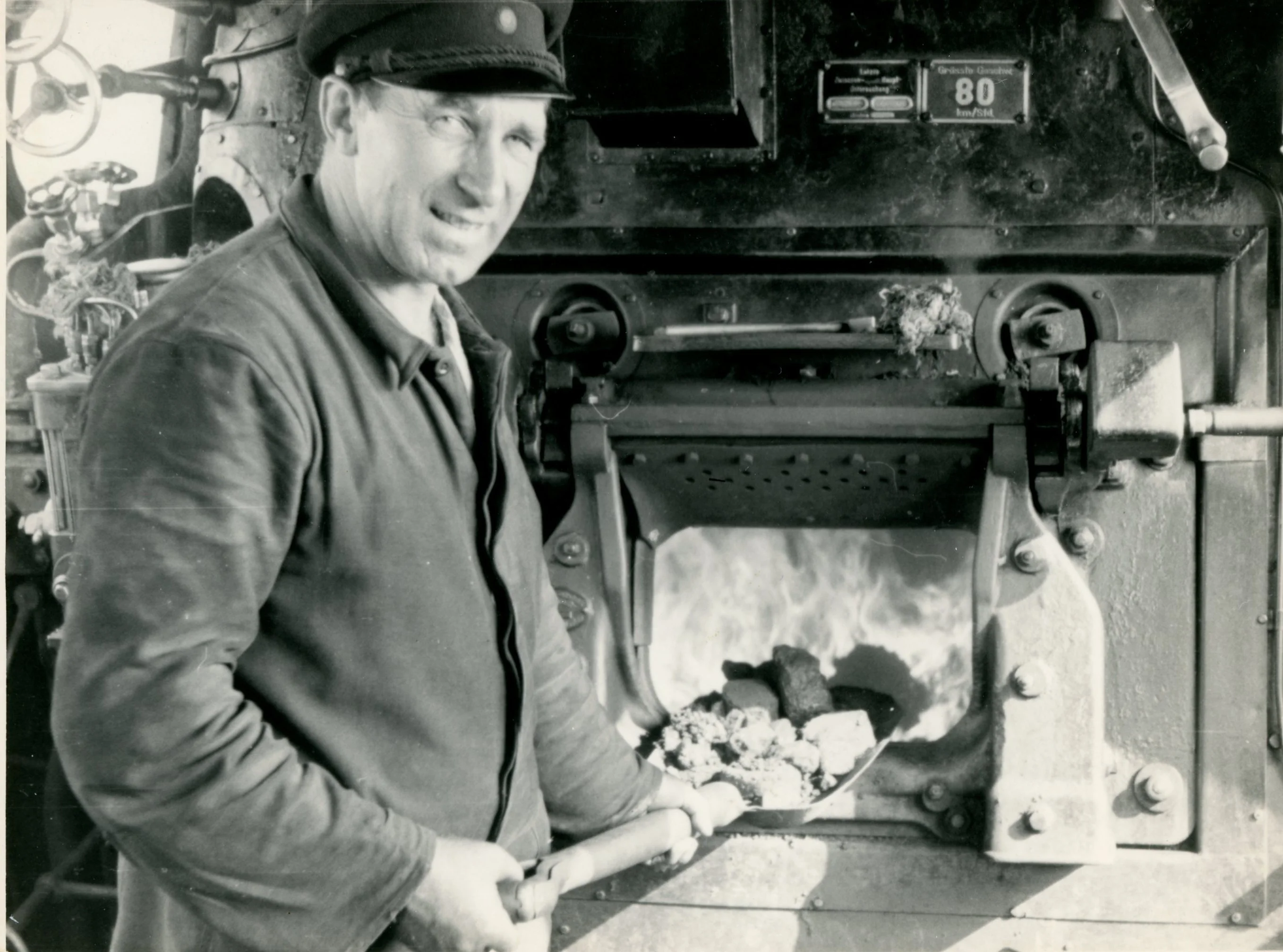 Ein Heizer schippt Kohle in eine Dampflokomotive
