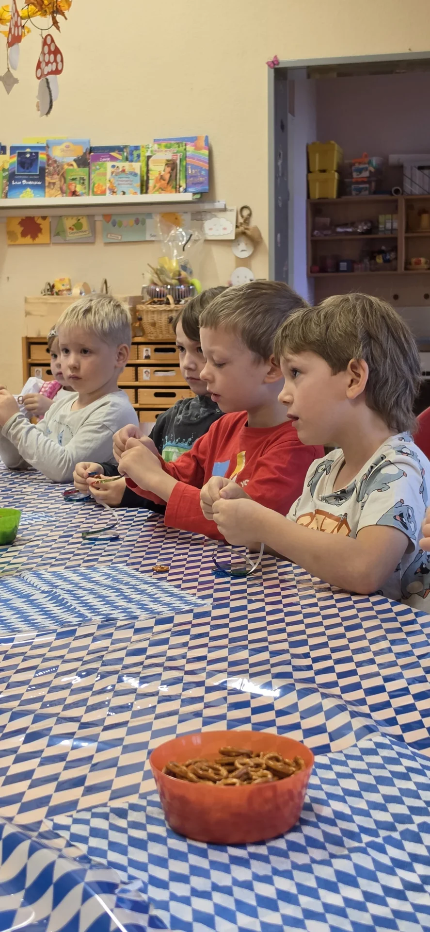 5 Kinder am Tisch fedeln sich eine Brezelkette