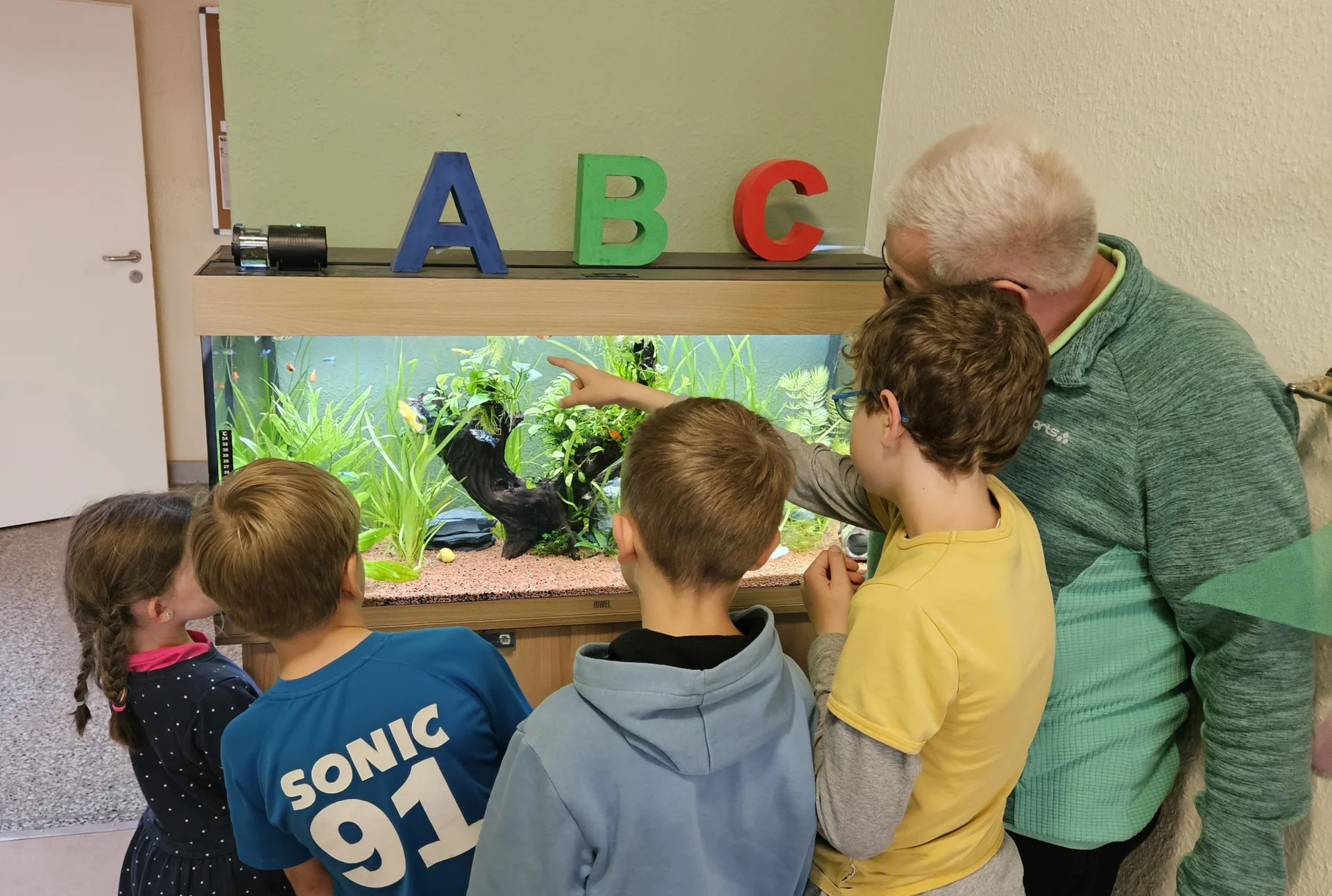 Schüler betrachten mit Herrn Hoffmann das Aquarium