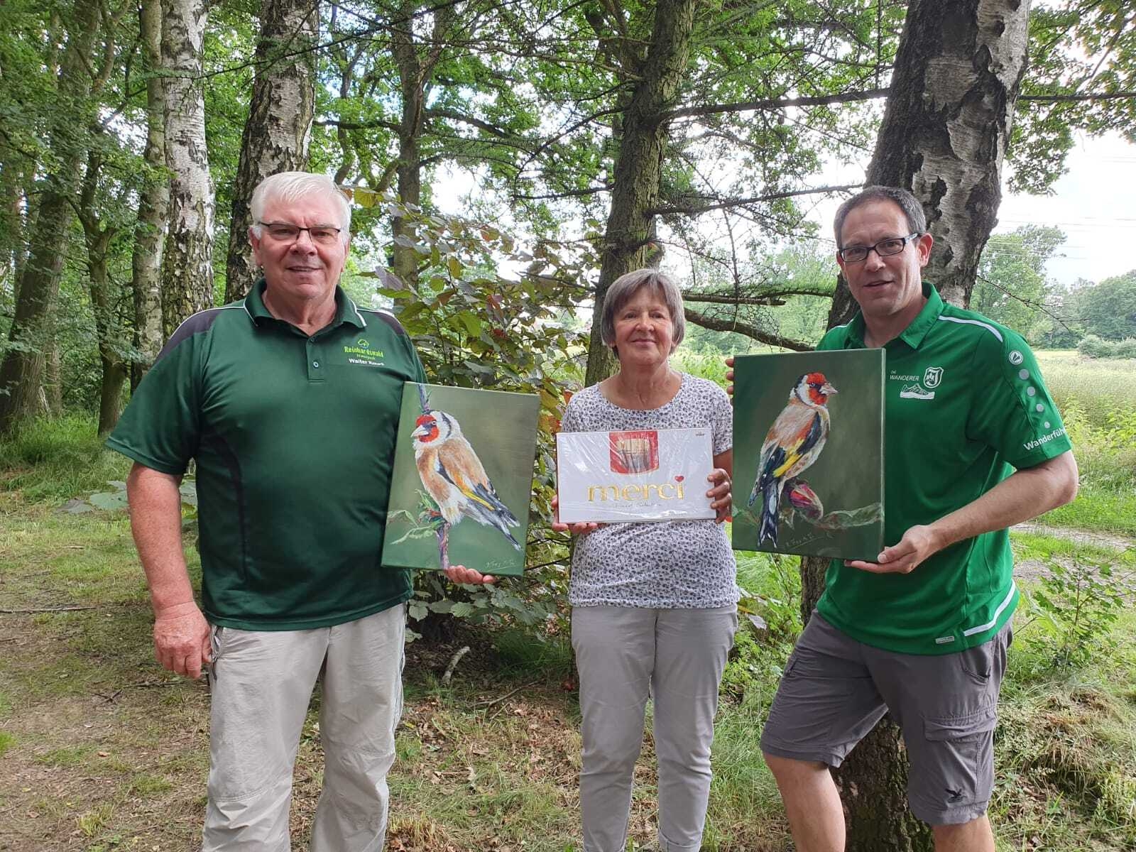 Bild: Dennis Krausgrill von den „Wanderern“ überreicht Walter und Helga Kouril zwei Bilder und eine große Packung Schokolade als Anerkennung für ihre Verdienste um den Vogel-Lehrpfad.