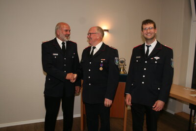 Kay Sierk vom Kreisfeuerwehrverband Pinneberg (v.l.) zeichnete B&uuml;rgermeister a.D. Claus Hell aus, Wehrf&uuml;hrer Lasse Kr&uuml;ger gratuliert 