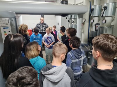 Sch&uuml;lerinnen und Sch&uuml;ler der 6. Klasse mit dem Hausmeister im Heizungskeller 