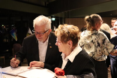 Die G&auml;ste, darunter Werner Duda von den Bischofsheimer Schmalfilm- und Videofreunden, tragen sich ins G&auml;stebuch ein.  (Bild vergr&ouml;&szlig;ern)