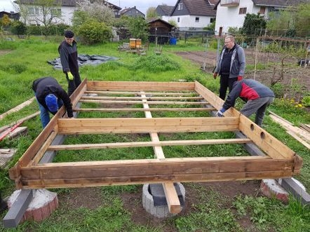 Bild: 6 Fundamentpunkte, 3 Tragebalken und erster Holzrahmen in Blockbauweise