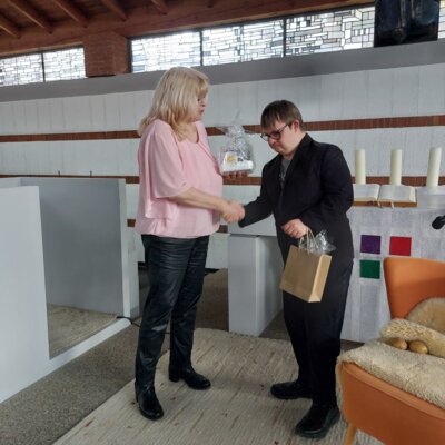 Petra Doering bedankt sich bei Henri Hirt. Beide reichen sich die Hand und Petra Doering &uuml;bergibt ein in Folie eingepacktes Geschenk. 