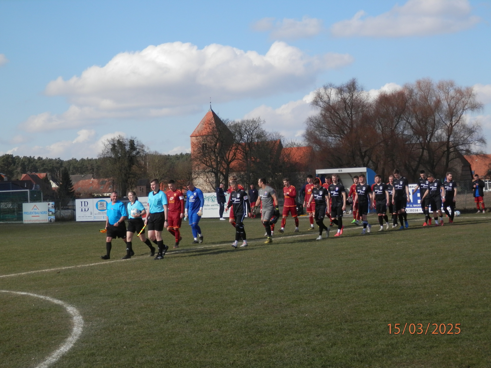 Bild: Schiedsrichterin Mathilda Reinsch führt die Teams aus Lohmen und Warin (schwarz) aufs Spielfeld. Vorne die beiden Mannschaftskapitäne Jakob Hafemann (l.) und Dennis Martens (r.).