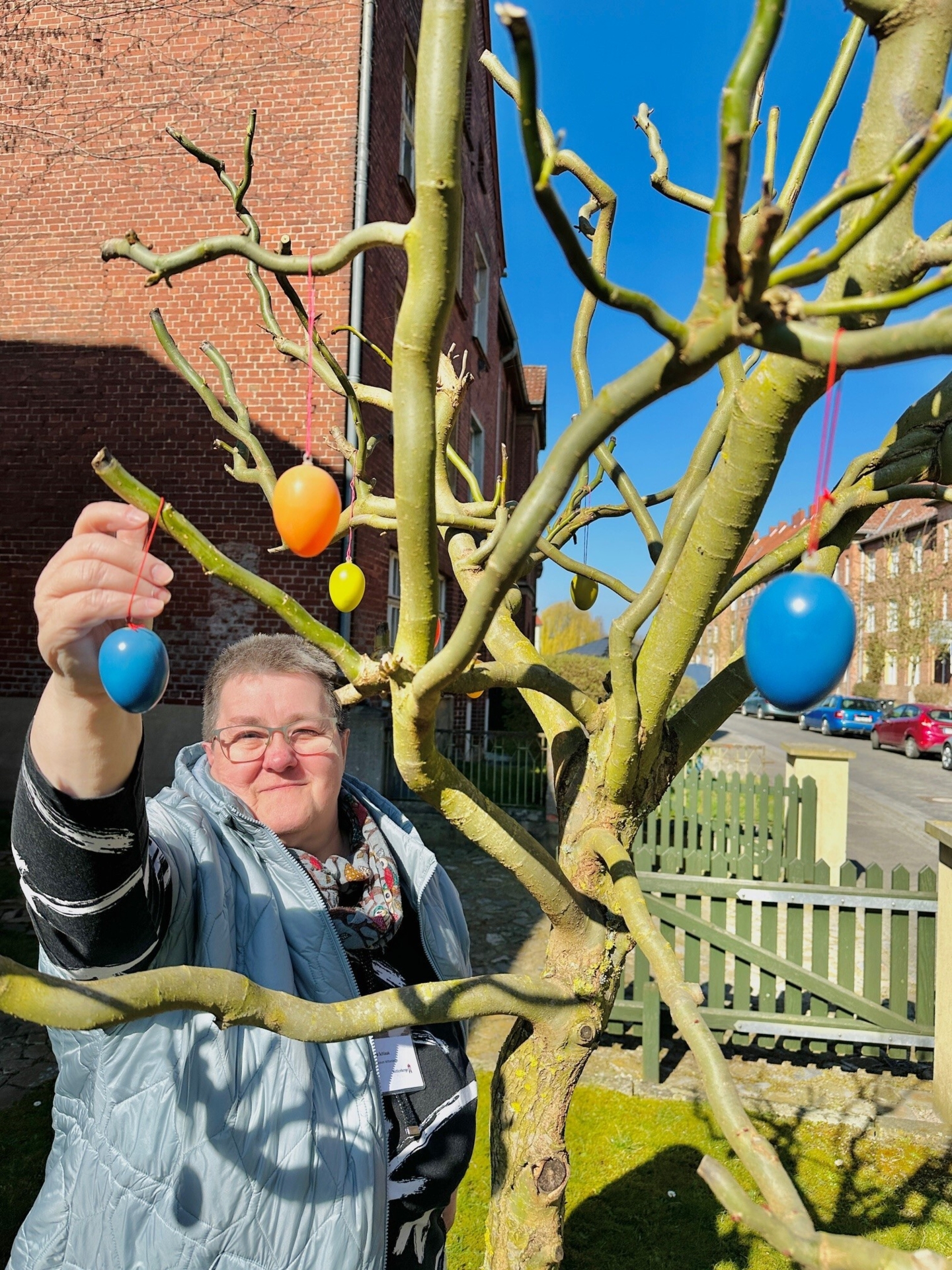 Bild: Mitarbeiterin Marina Schlaak schmückt einen Baum im Vorgarten des Museums