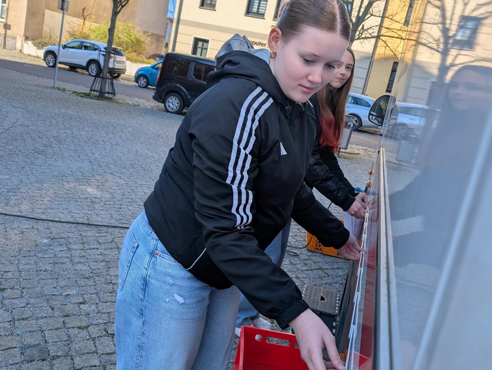 Bild: Marie Jochim (hinten) und Emily Polenz beim Ausmessen eines Standes auf dem Wochenmarkt. Foto: Stadt Calau / Jan Hornhauer