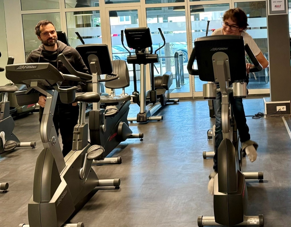 Bild: Ein Schüler und eine Begleitung auf einem Ergometer