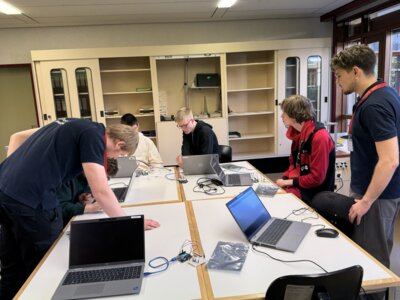 Sch&uuml;ler:innen der EWS sitzen gemeinsam mit Azubis von Trumpf-H&uuml;ttinger an Laptops und programmieren  (Bild vergr&ouml;&szlig;ern)