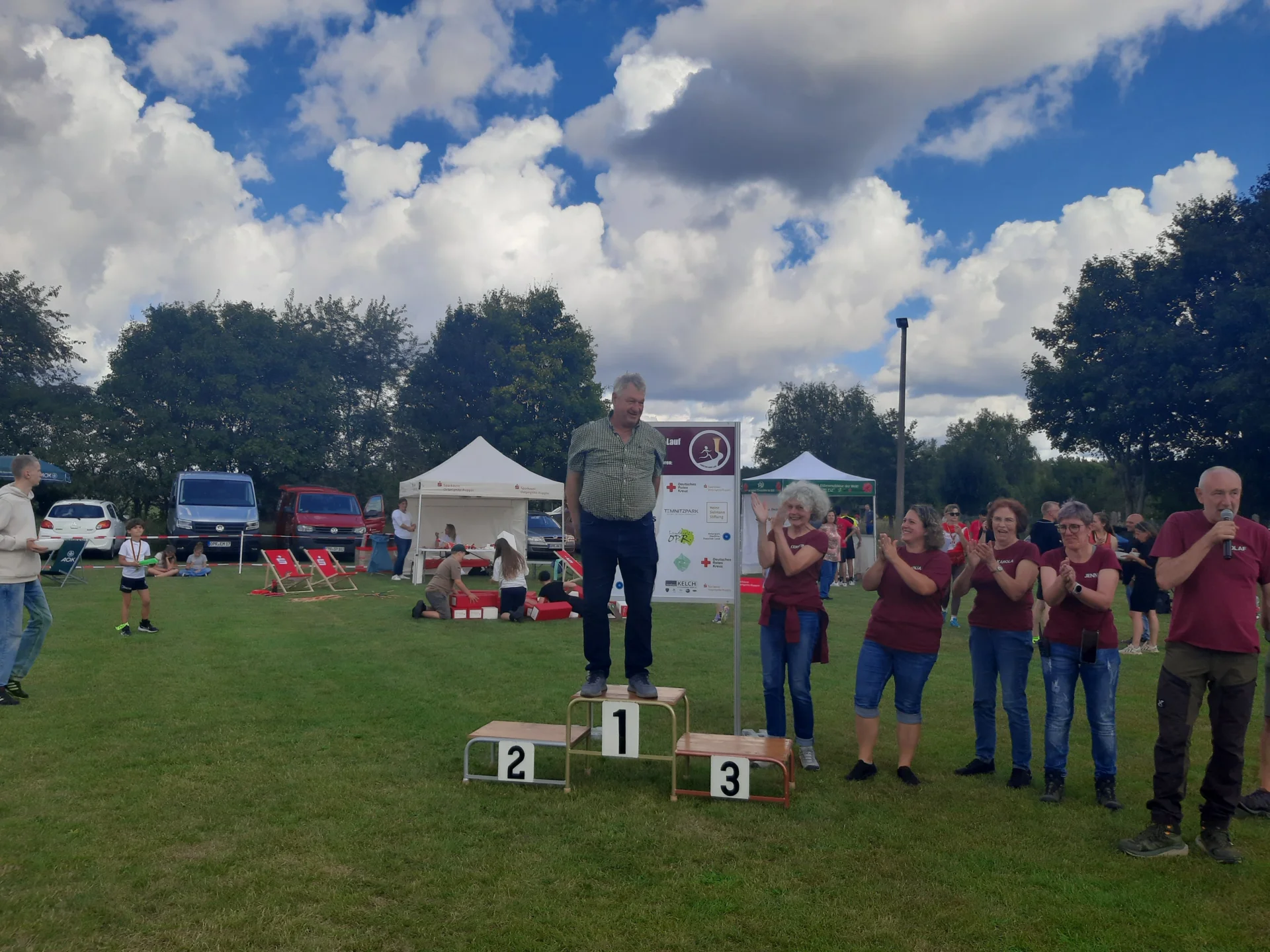 Bild: Bürgermeister Bernd Müller als Wettsieger auf dem Siegertreppchen, bejubelt vom Orga-Team