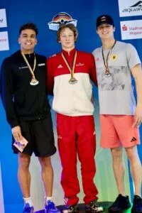 Vorschaubild: Maximilian Warkentin (SG Frankfurt, Mitte) bei der Siegerehrung mit Michael Raye (links) und Luca Nik Armbruster (rechts) 100 Lagen, Foto: S. Sonnenschei