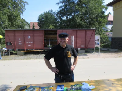Mann steht an einem Tisch mit Info-Brosch&uuml;ren vor dem Wagon  (Bild vergr&ouml;&szlig;ern)