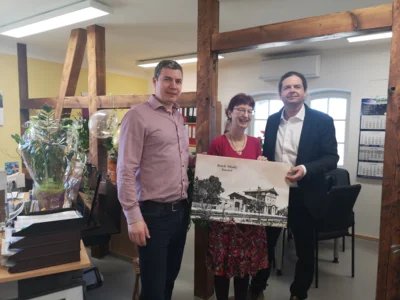 Amtsdirektor Mathias Ryll &uuml;berreicht AZV-Chefin Kerstin Baier ein Bild des Bahnhofs vor 100 Jahren, das freut auch B&uuml;rgermeister Matthias Schimanowski  (Bild vergr&ouml;&szlig;ern)