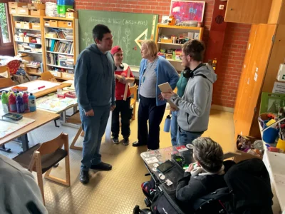 Lehrerin erkl&auml;rt Sch&uuml;ler:innen den Arbeitsauftrag im Werkraum  (Bild vergr&ouml;&szlig;ern)