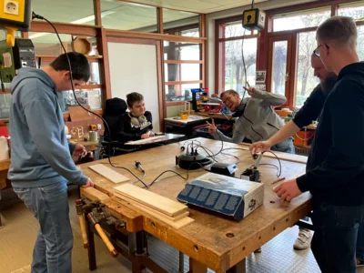 Sch&uuml;ler:innen um einen Werktisch bei der Arbeit  (Bild vergr&ouml;&szlig;ern)