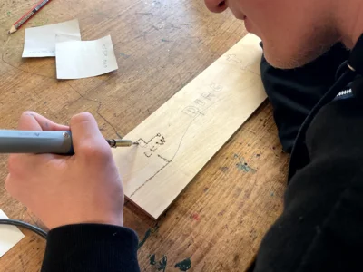 Ein Sch&uuml;ler mit einem L&ouml;tkolben beim Brennen in eine Holztafel  (Bild vergr&ouml;&szlig;ern)