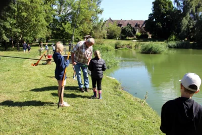 Stationsbetreuer Gerd Jentsch hebt den Fang vorsichtig mit dem Unterfangkescher aus dem Wasser 