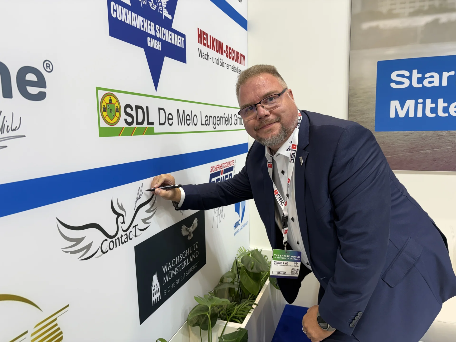 Bild: Stefan Laib (Contact Sicherheitsdienst GmbH & Co KG) beim Signieren des Unternehmenslogos.