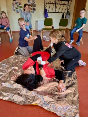 Kinder und Kursleiterin sitzen im Stuhlkreis im Gemeindehaus 